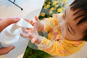 Asian cute baby using handÂ sanitizer